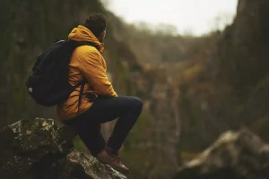 man hiking in yellowcoat and backpack