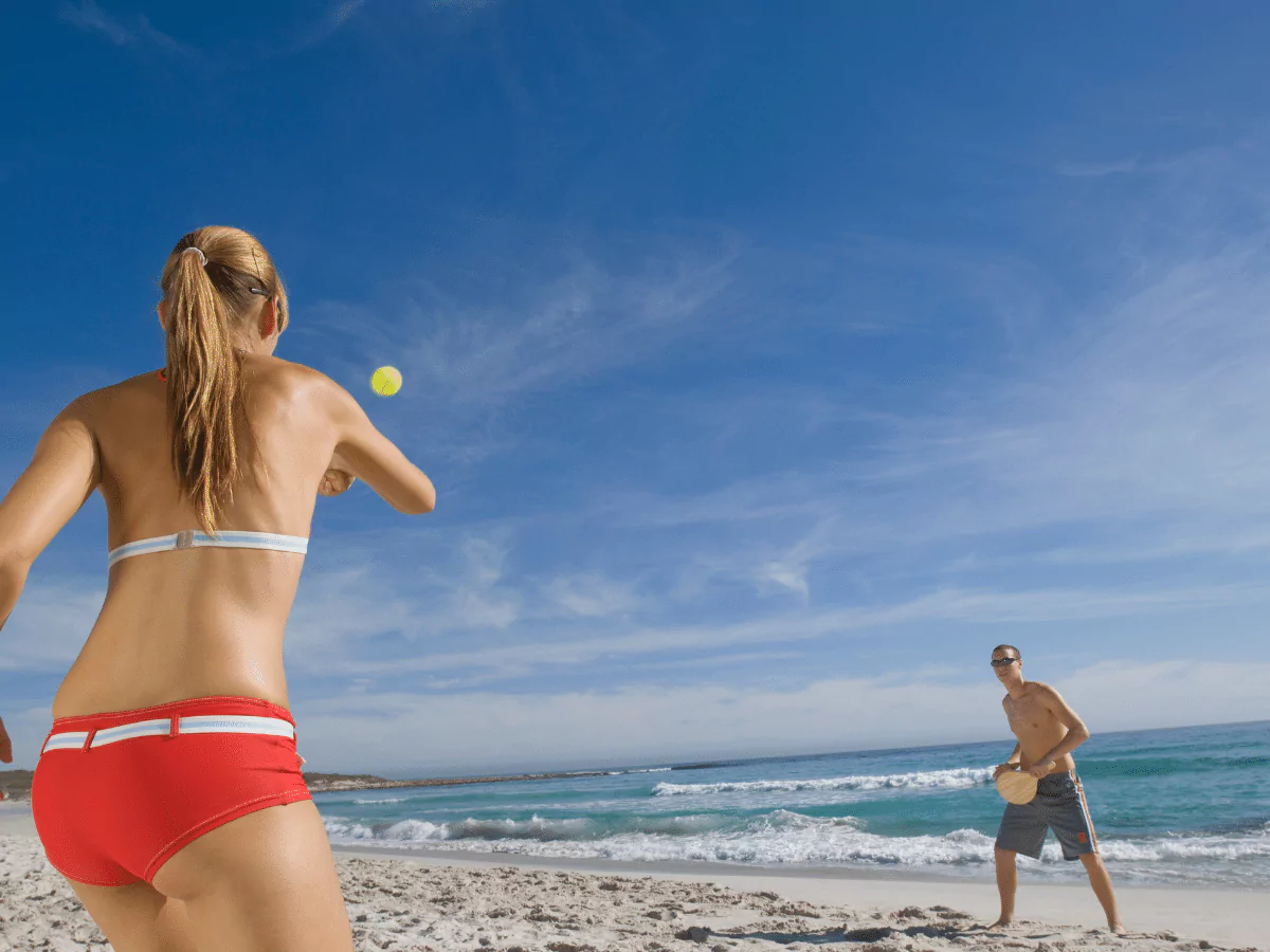 woman in bikini playing a beach paddle game
