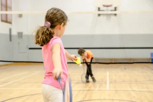 2 kids playing badminton with rackets and shuttlecock