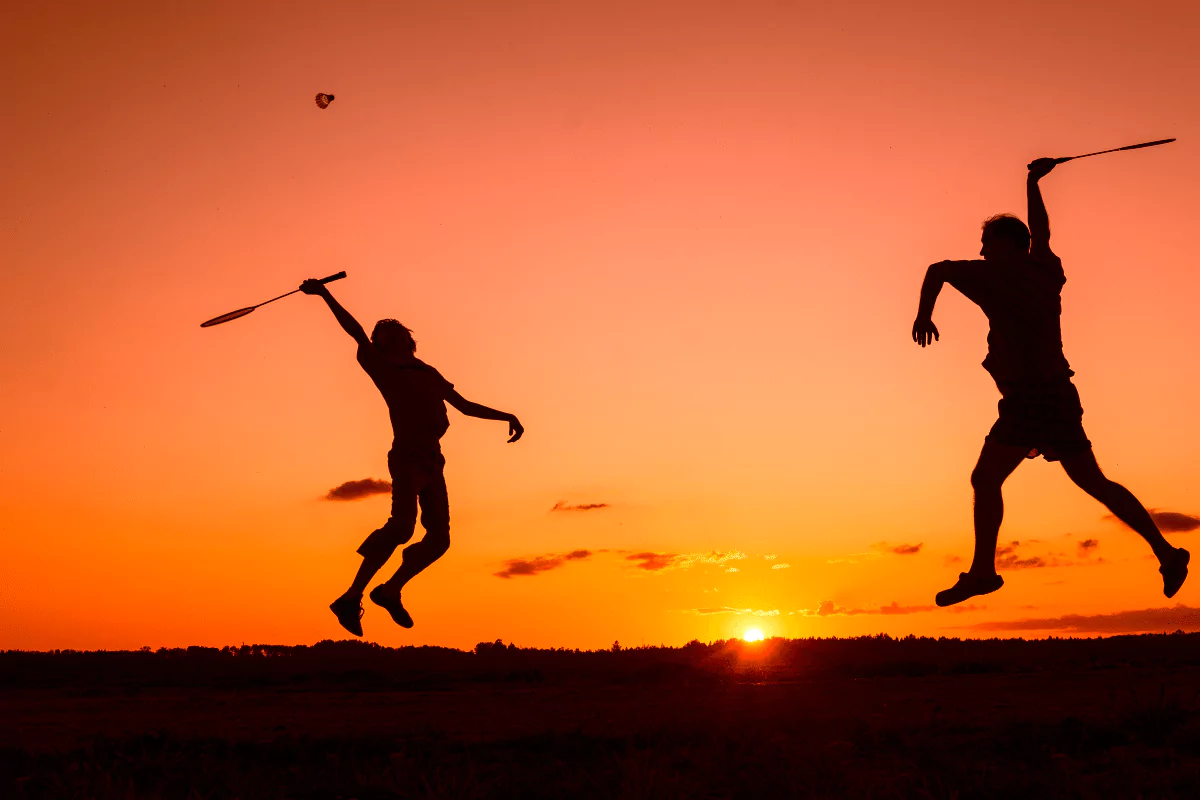 sunset playing badminton, 2 people with racquets