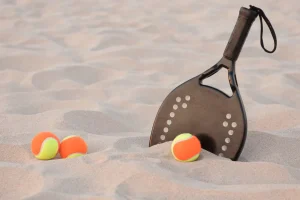 3-beach-tennis-balls-and-beach-tennis-racquet-in-sand, beginners equipment