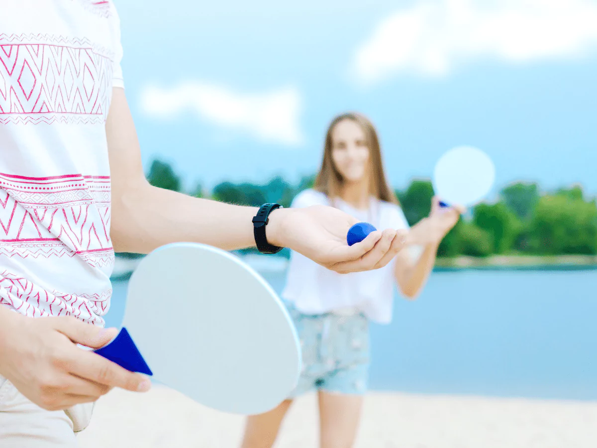 2 people playing with paddles on the beach