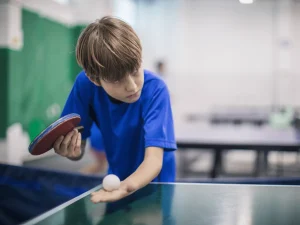 boy serving table tennis ball