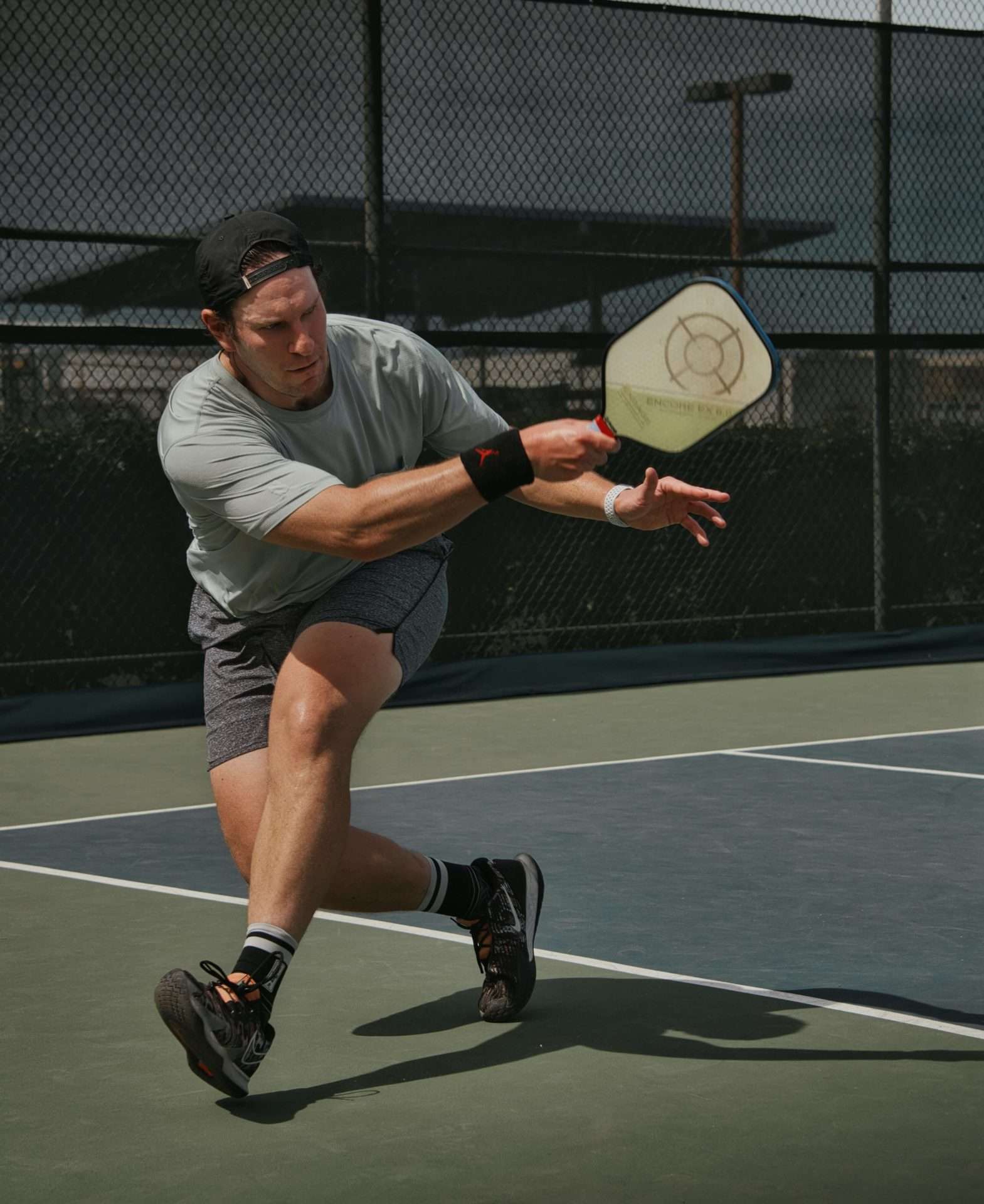 man playing pickleball, shooting the ball, holding pickle ball racket