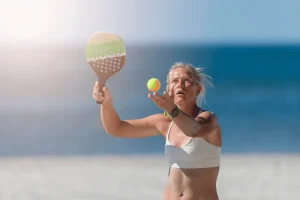 younger-woman-playing-beach-tennis-serving-the-ball