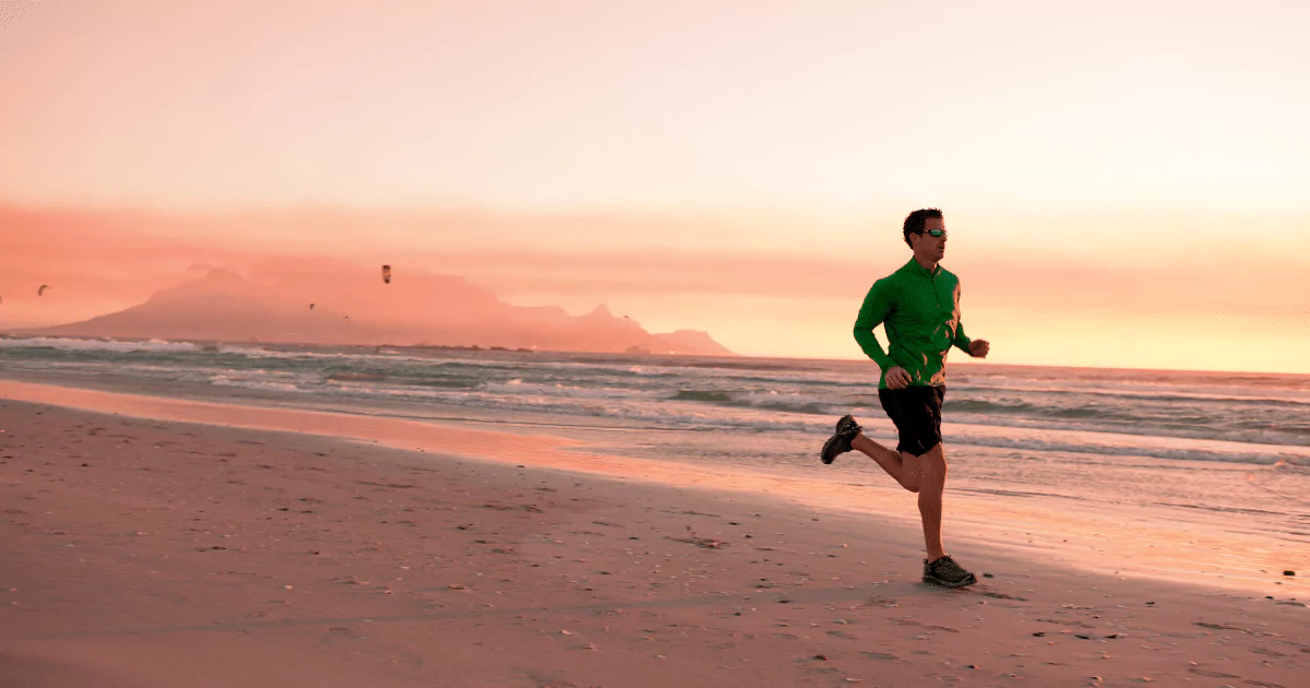 man running on beach with green jacket 6489c14f4c46b