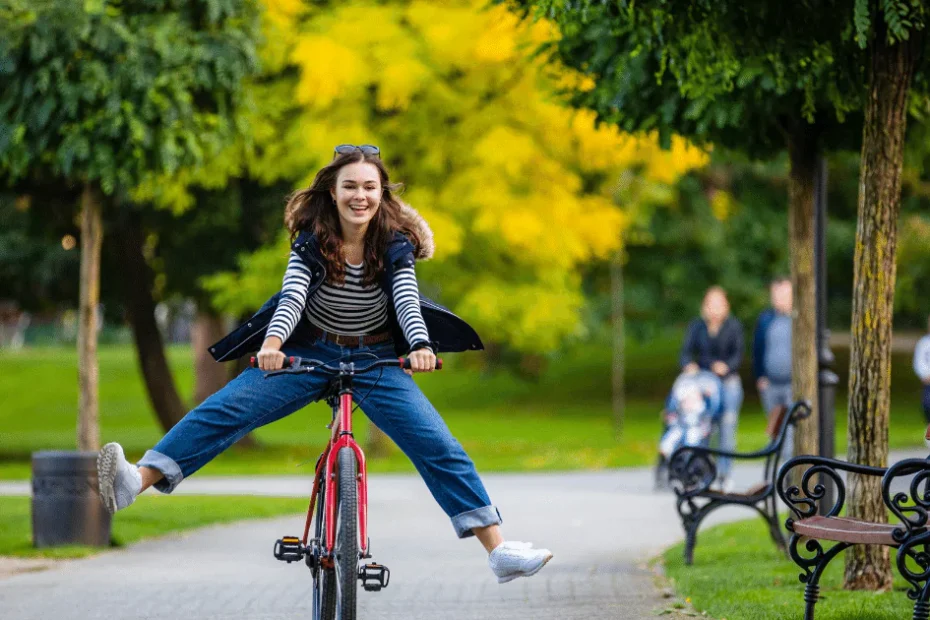 A woman is riding a bike in a park of different types.