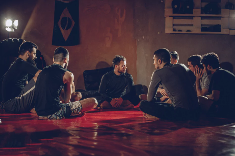 A group of people practicing martial arts on the floor in a dark room.
