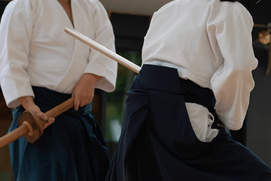 2 people performing martial arts in white. wooden swords