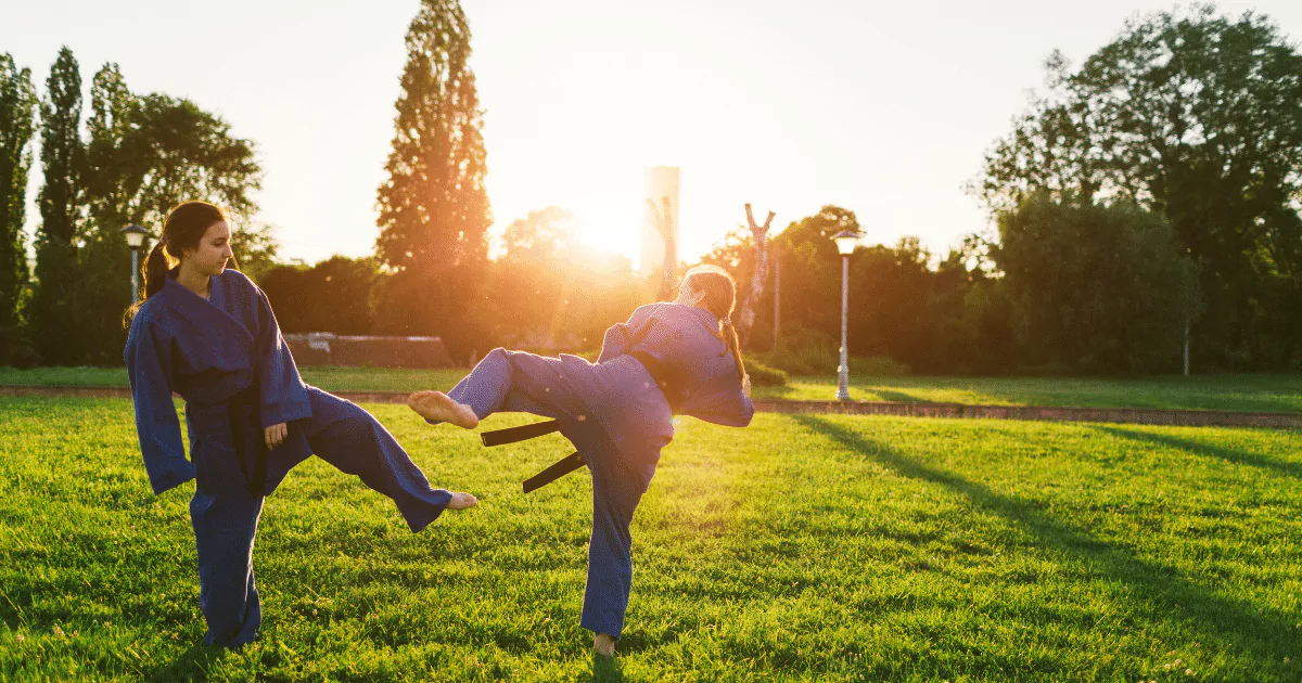 Two people practicing Aikido in a park at sunset to experience its benefits.