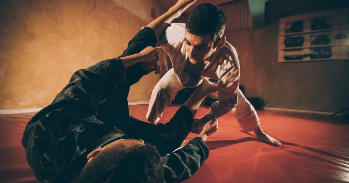 2 men on red mat in a hold, systema, Brazilian jiu jitsu