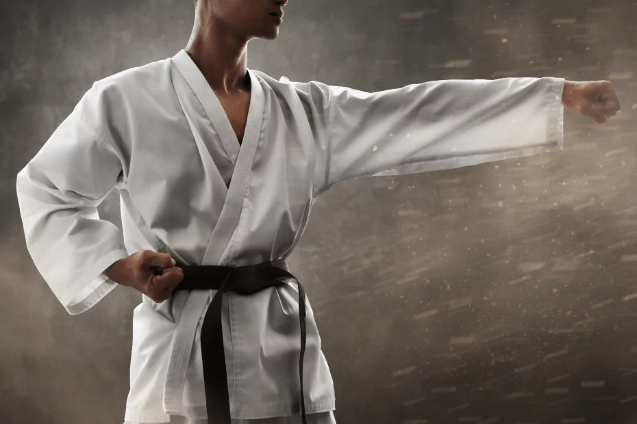 person in white robe, black belt, punching air