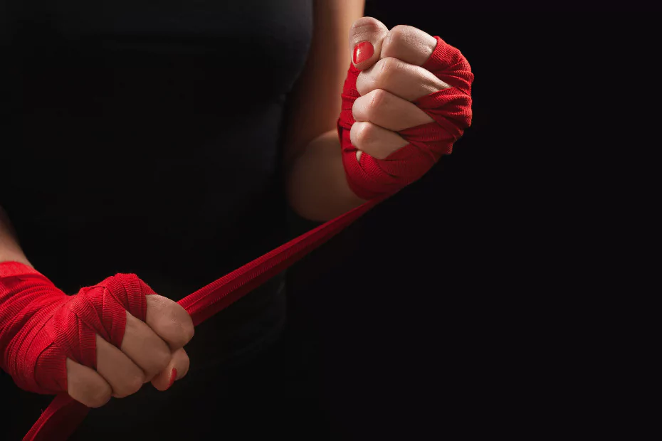 A woman showcasing martial arts skills wearing red boxing gloves on a black background.