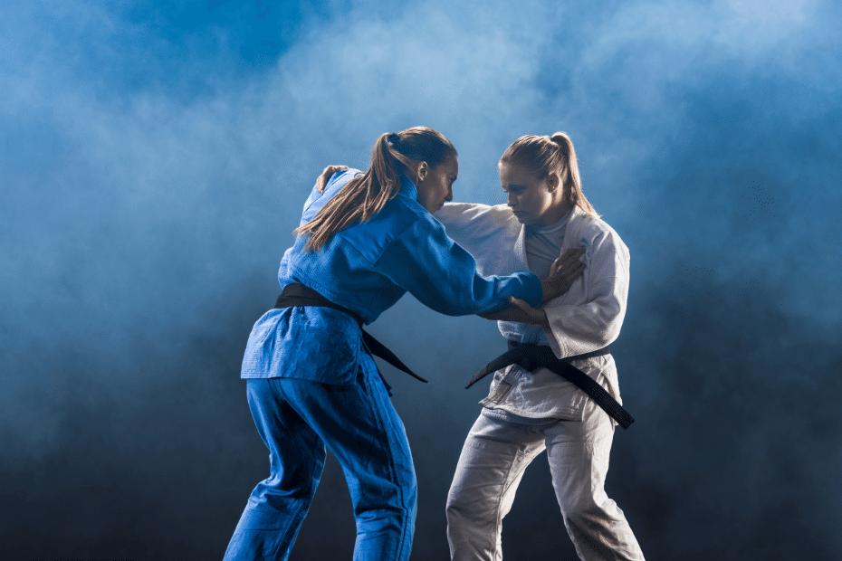 Two women in blue judo uniforms fighting on a blue background