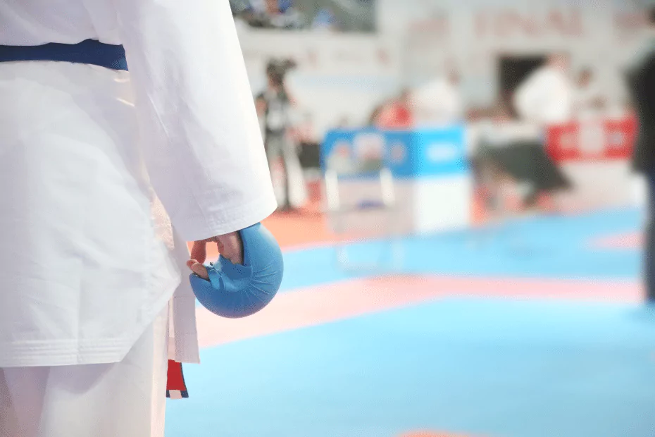 blue glove on person in white robe. blue mat in background
