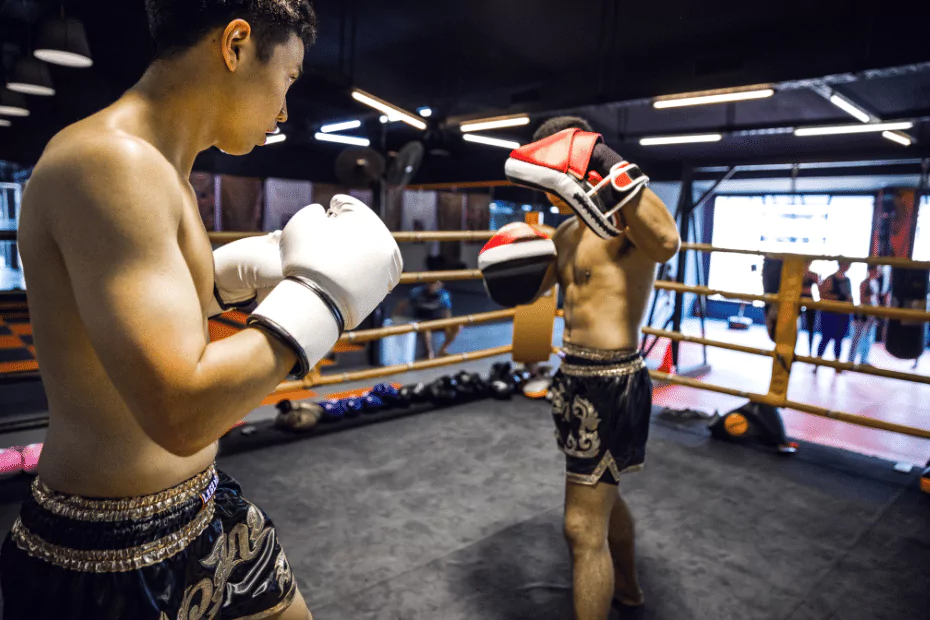 Two men in a boxing ring practicing muay thai