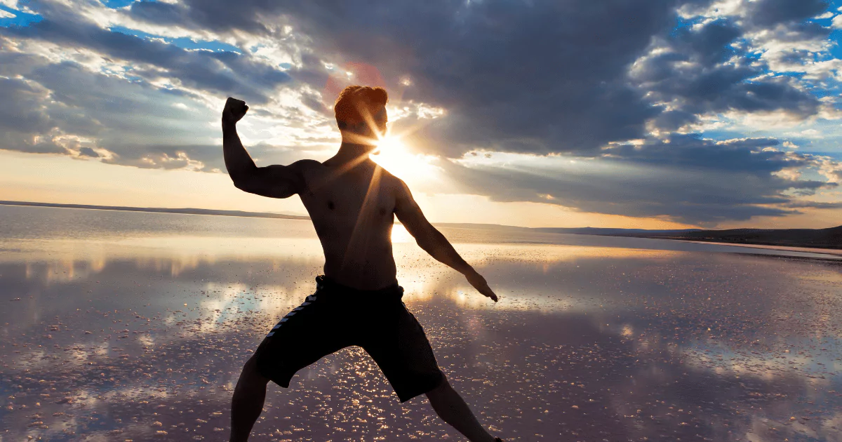 shirtless man on beach in kickboxing pose