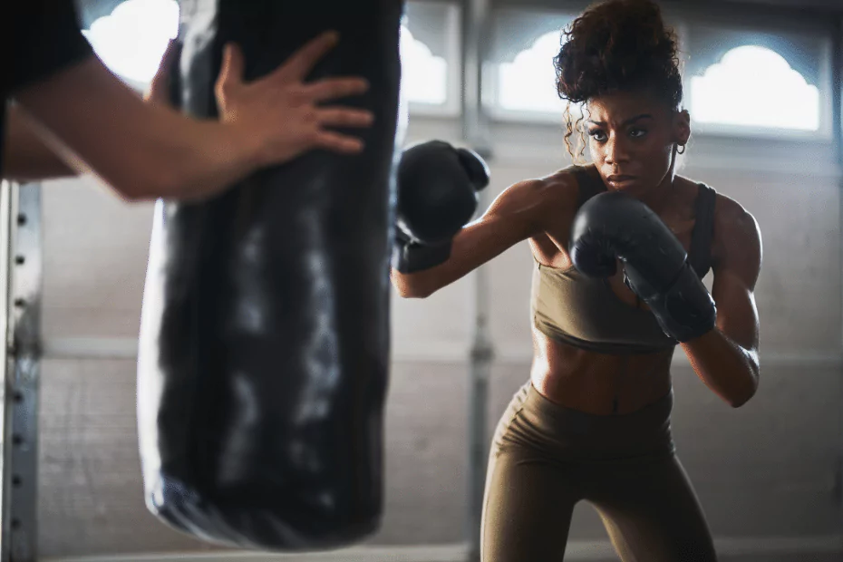 A woman is practicing boxing techniques on a bag at the gym