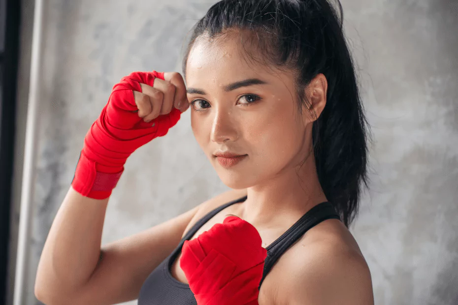 A young woman in muay thai gloves posing for a photo