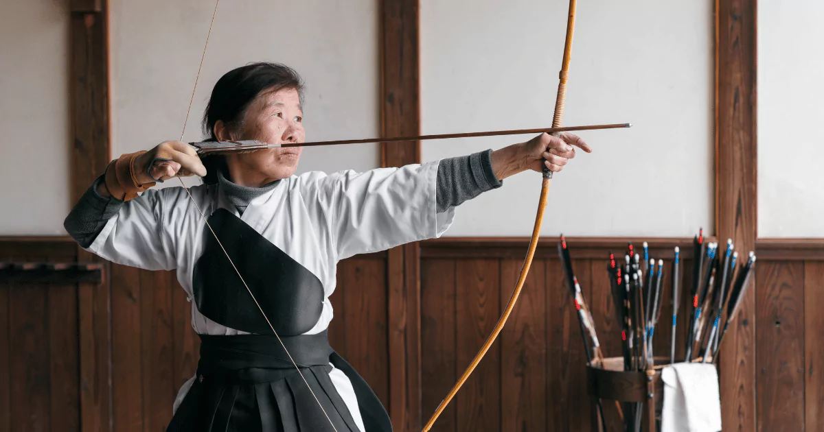 An asian woman mastering archery in a room
