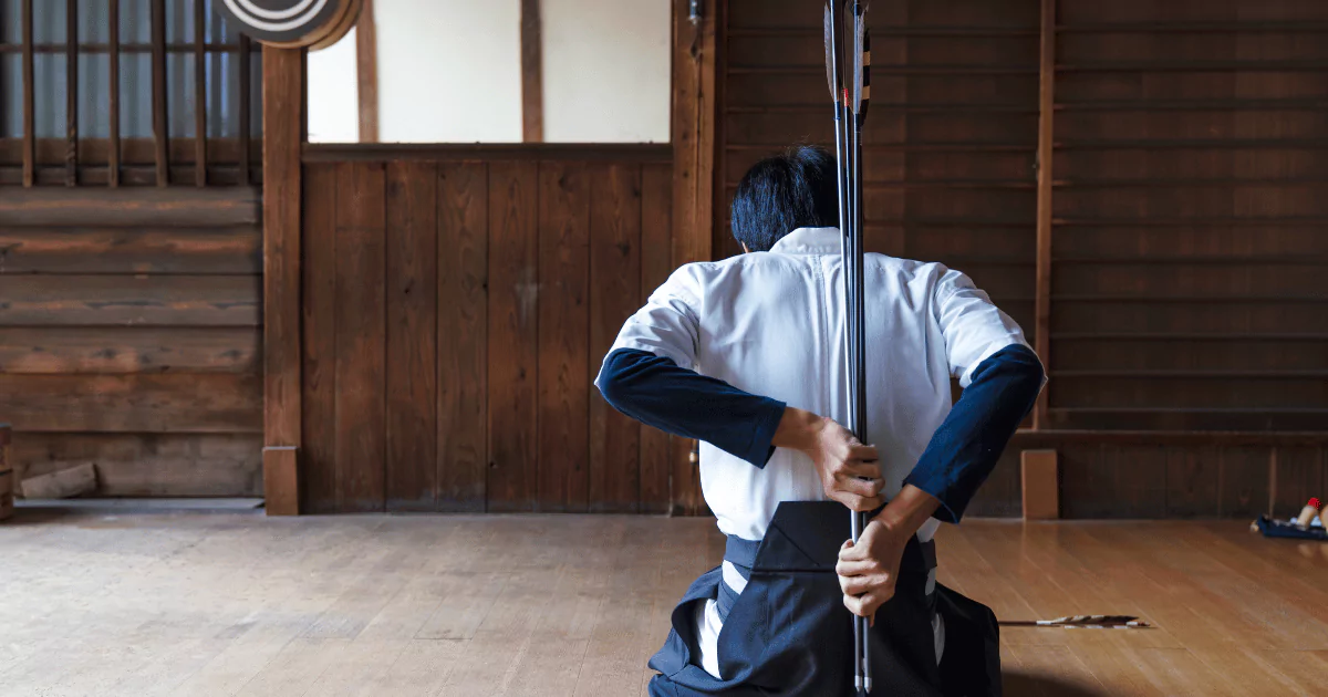 A man practicing Kyudo with a sword in a wooden room
