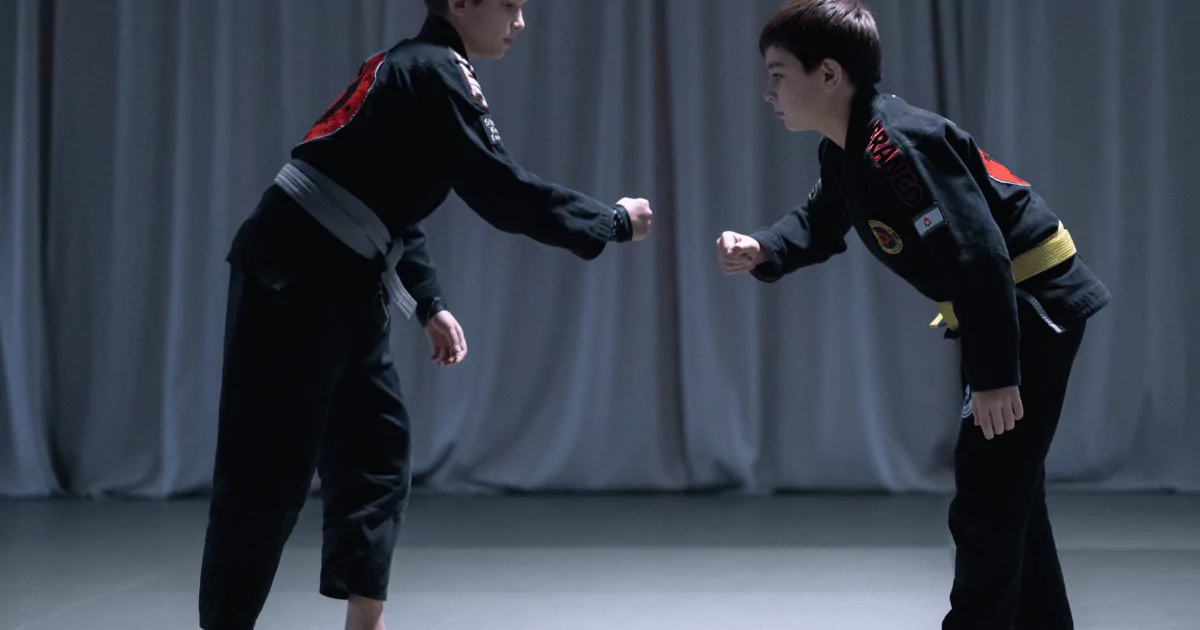Two boys in black karate uniforms practicing Brazilian Jiu Jitsu