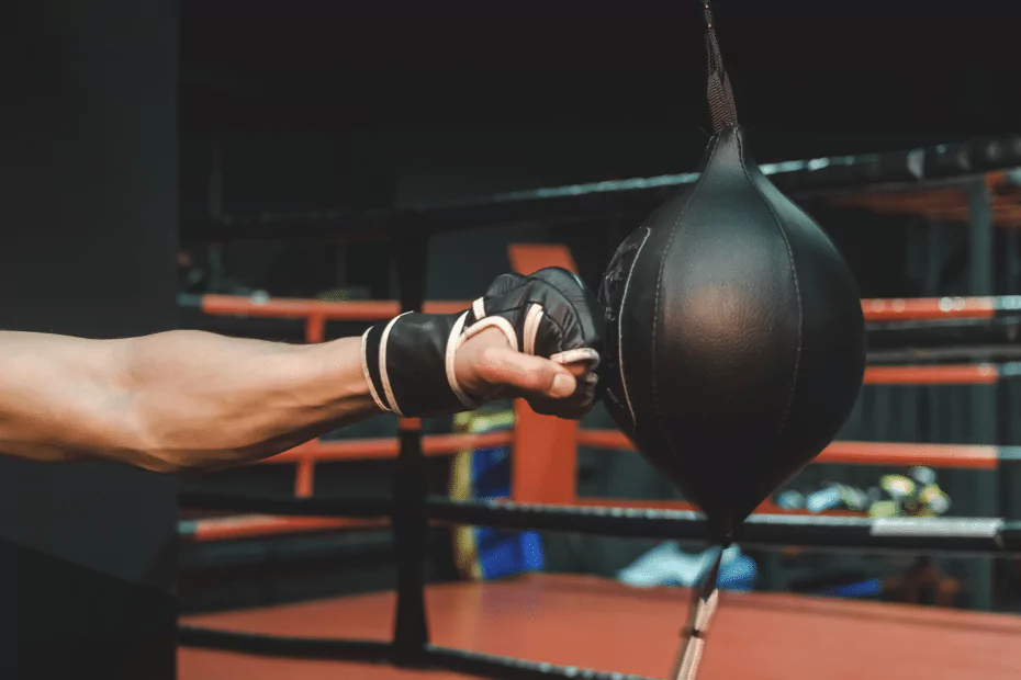A man demonstrating boxing technique by punching a bag in a ring