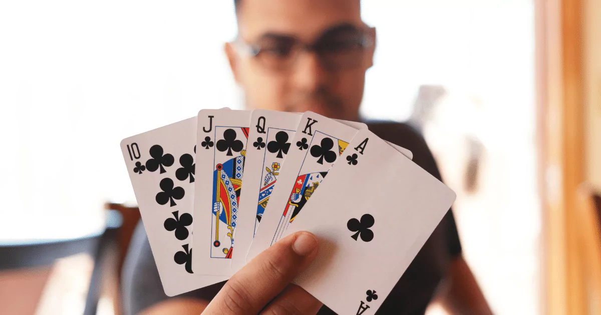 person holding a royal flush of clubs