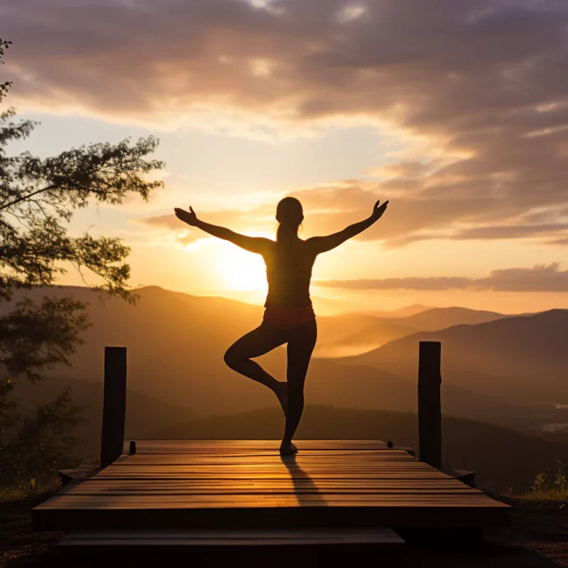 A woman practices self care as she does yoga on a dock at sunset
