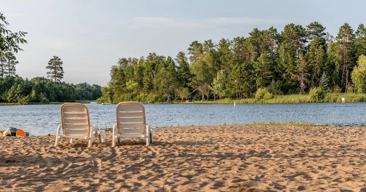Two chairs on the sand near a lake