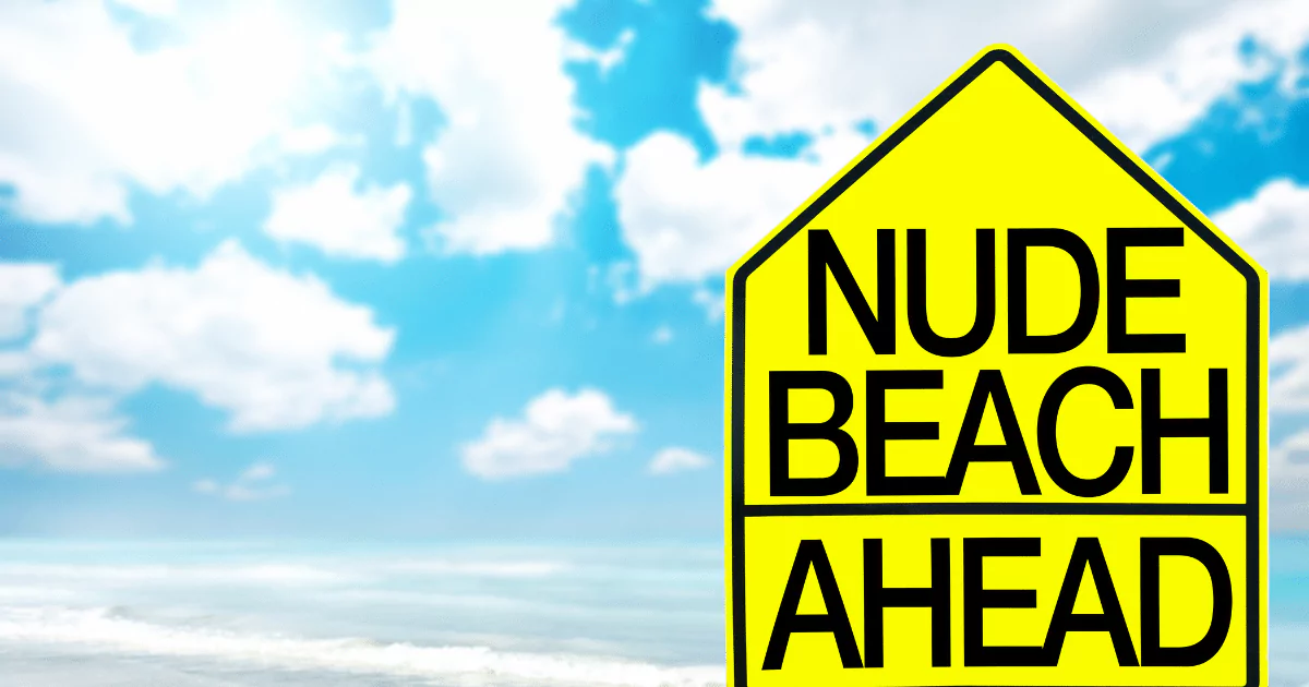 Beach sign says "nude beach ahead in bright yellow