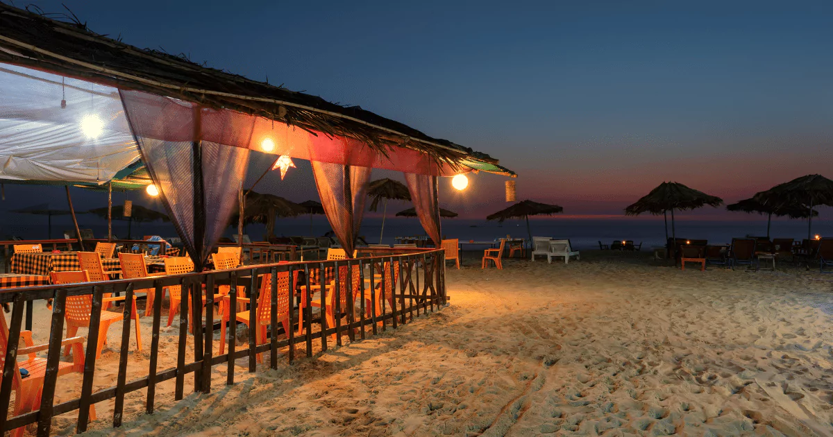 A beachfront restaurant at dusk, sand drinking bar
