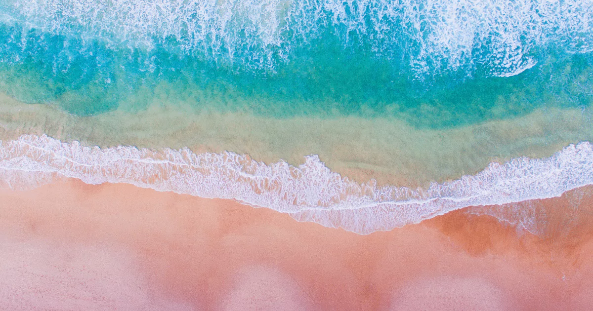 An aerial view of a beach with colorful pink sand